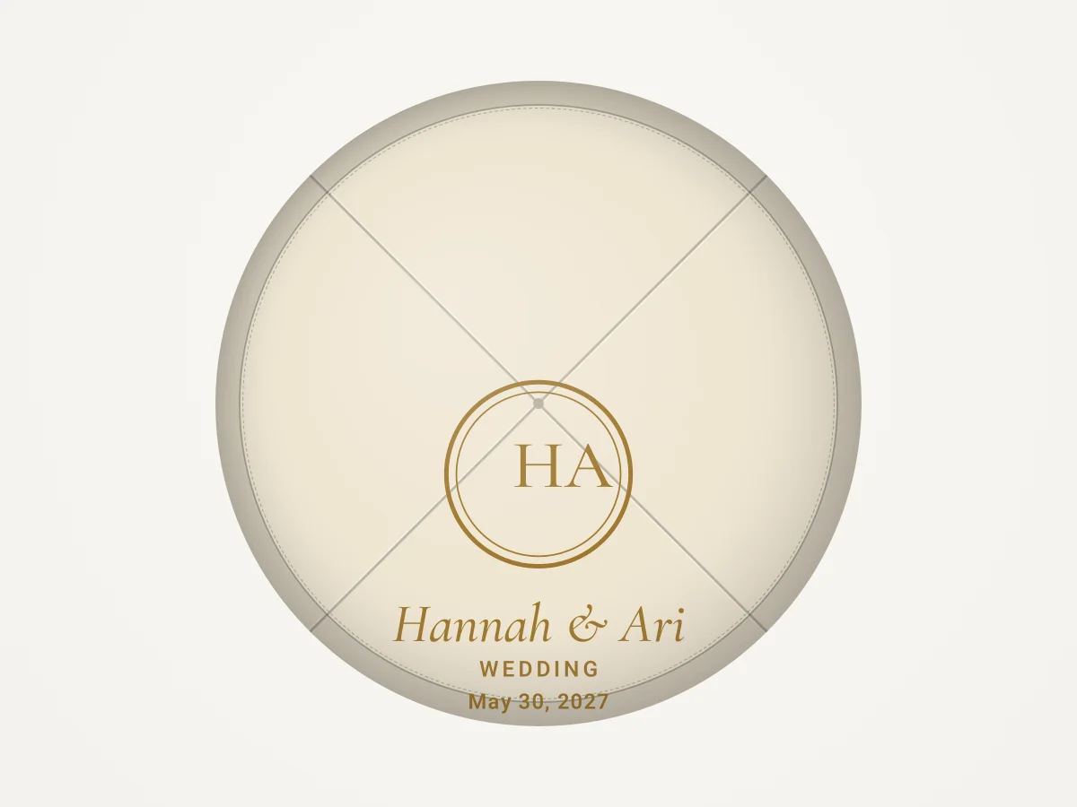 A flat proof of an ivory kippah from above, with a gold monogram and the names Hannah and Ari