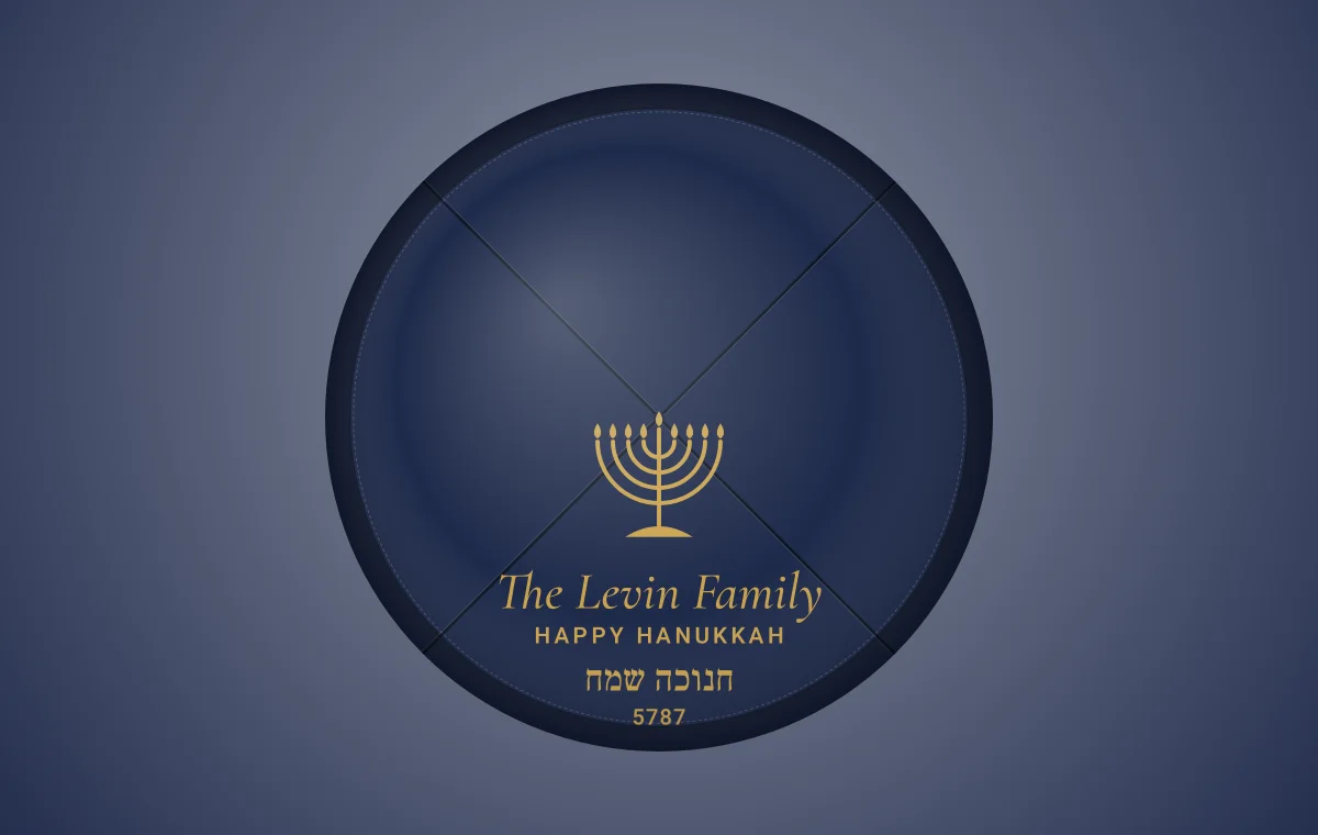 Flat proof of a navy kippah with a gold menorah and the words Happy Hanukkah, on a dark background